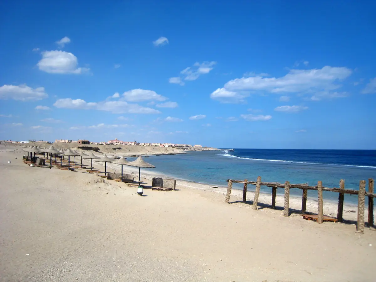 Sandy beach with wooden posts and bright blue sea under a blue sky