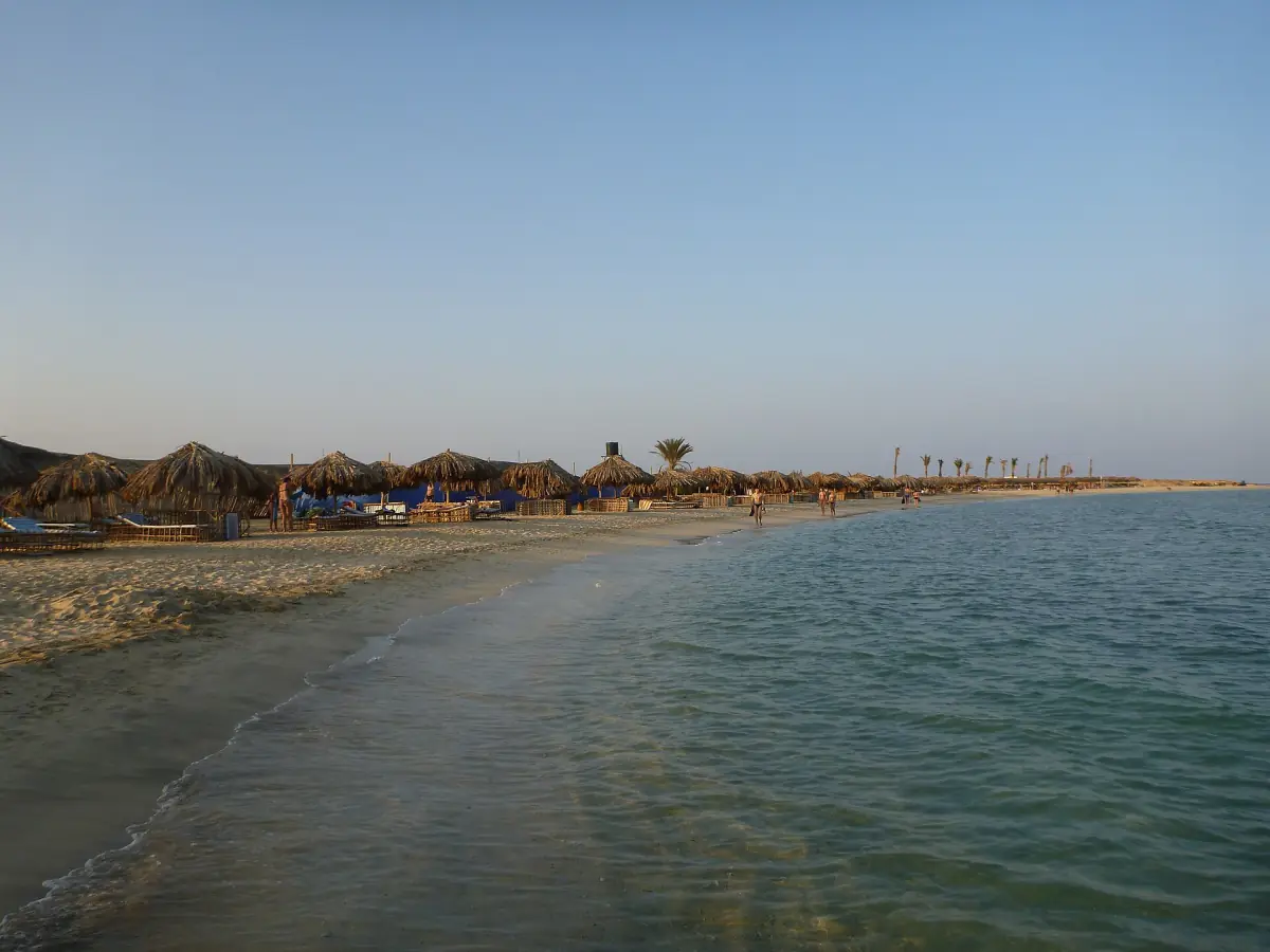 Calm bay and long sandy beach with low dunes behind