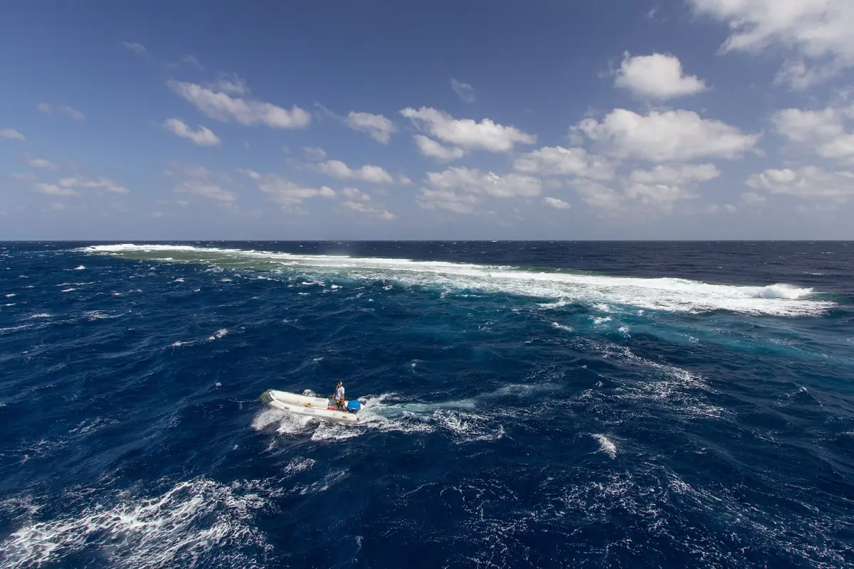 Waves breaking on an offshore reef with a small boat nearby