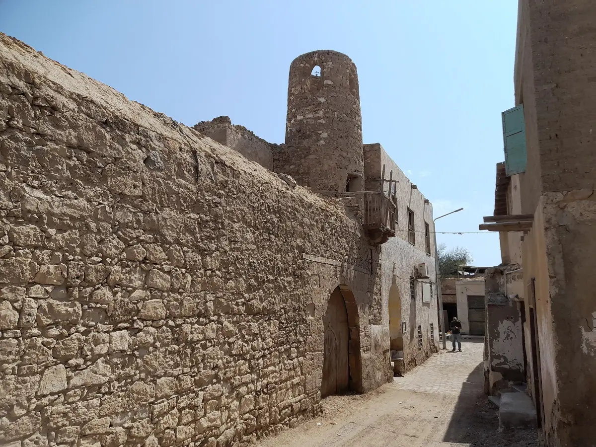 A narrow lane between old stone walls with a small tower