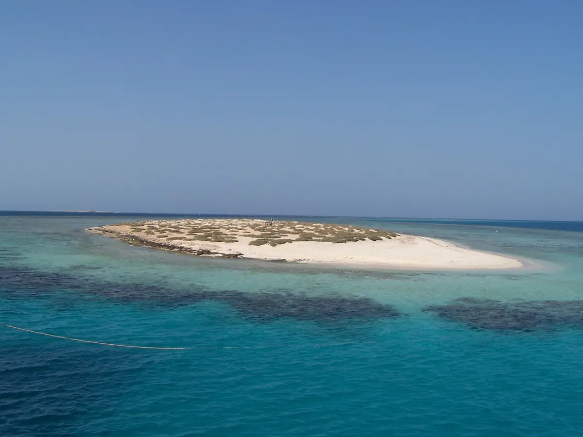 A small white sand island surrounded by turquoise shallows and reef on the Red Sea