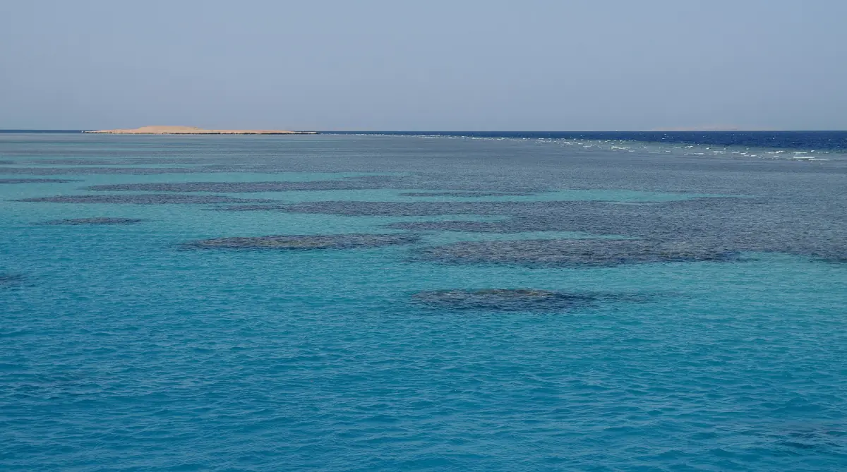 Coral reef shallows seen from the water surface under a hazy sky