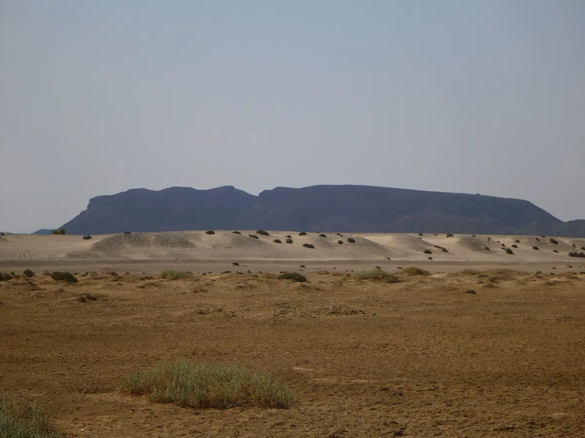 Flat desert plain with a table mountain on the horizon