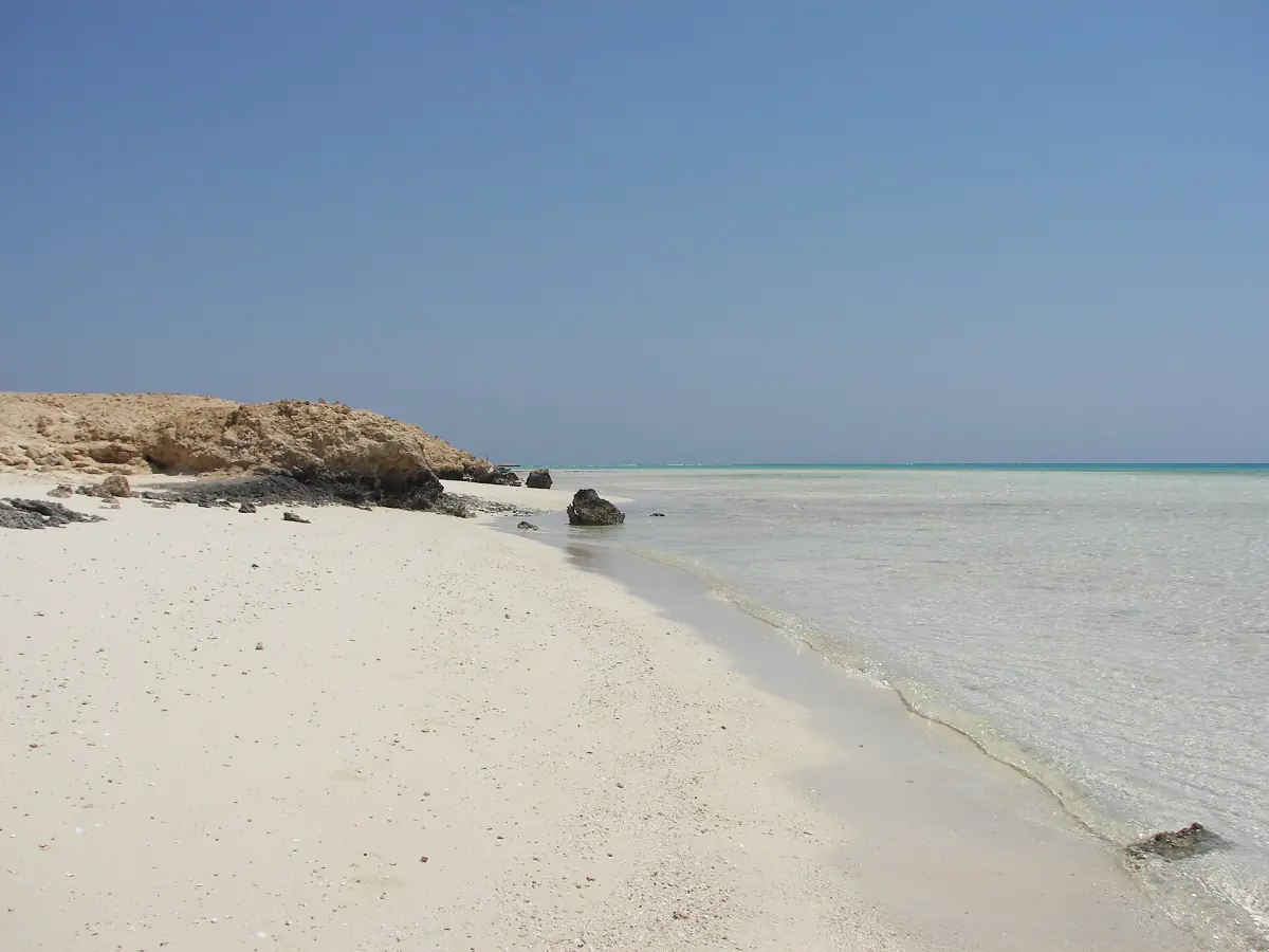 White sand beach with clear shallow water and a rocky headland on the Egyptian Red Sea